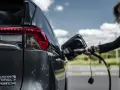 Kobieta podłącza ładowarkę do hybrydowego SUV-a. Zastanawiasz się, ile kosztuje ładowanie elektryka?