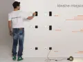 Mężczyzna pokazuje na ścianie, na jakiej wysokości gniazdka powinny być umieszczone: 150 cm dla informacji, 110-120 cm dla akcji, 30 cm dla zasilania.