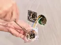 Instalator podłącza podwójny włącznik światła, pokazując jak podłączyć włącznik światła podwójny trzy przewody.