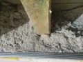 Drewniana belka i luźna, szara celuloza ocieplenie w przestrzeni między stropowej. Metalowa siatka pod izolacją.