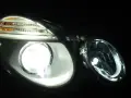 Jasny ksenon rozświetla reflektor, ukazując jego nowoczesny design i pomarańczowe kierunkowskazy.
