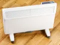 Biały grzejnik elektryczny na kółkach, idealny jako jaki grzejnik elektryczny do pokoju 25m2. Cyfrowy panel sterowania.