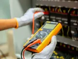 Elektryk sprawdza instalację multimetrem. Poznaj wymiana instalacji elektrycznej koszt i dowiedz się, jak uniknąć nieprzewidzianych wydatków.