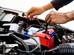 Mechanik sprawdza, jak sprawdzić co pobiera prąd w samochodzie, mierząc napięcie na akumulatorze.