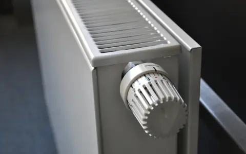 Biały grzejnik z termostatem ustawionym na 3. To element ogrzewania elektrycznego mieszkania, zapewniający komfort cieplny.