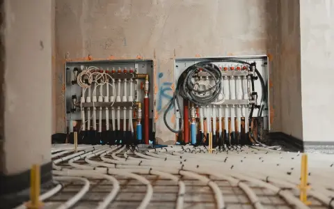 Instalacja ogrzewania podłogowego w bloku: rozdzielacze i rury gotowe do zalania betonem.