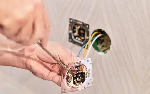 Instalator podłącza podwójny włącznik światła, pokazując jak podłączyć włącznik światła podwójny trzy przewody.