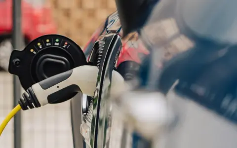 Ładowanie samochodu elektrycznego do 30 tys. zł. Wtyczka z żółtym kablem podłączona do portu ładowania.