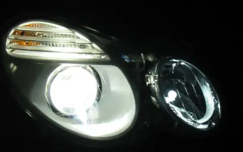 Jasny ksenon rozświetla reflektor, ukazując jego nowoczesny design i pomarańczowe kierunkowskazy.
