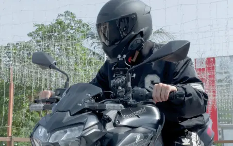 Motocyklista w kasku siedzi na motocyklu Kawasaki, z zamontowanym interkomem na kasku.