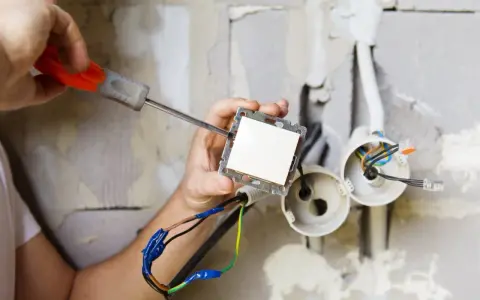 Elektryk montuje włącznik światła. Zastanawiasz się, ile kosztuje prąd budowlany?