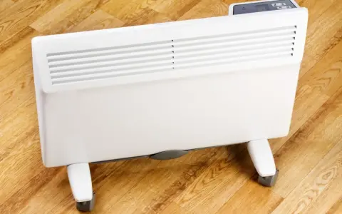 Biały grzejnik elektryczny na kółkach, idealny jako jaki grzejnik elektryczny do pokoju 25m2. Cyfrowy panel sterowania.