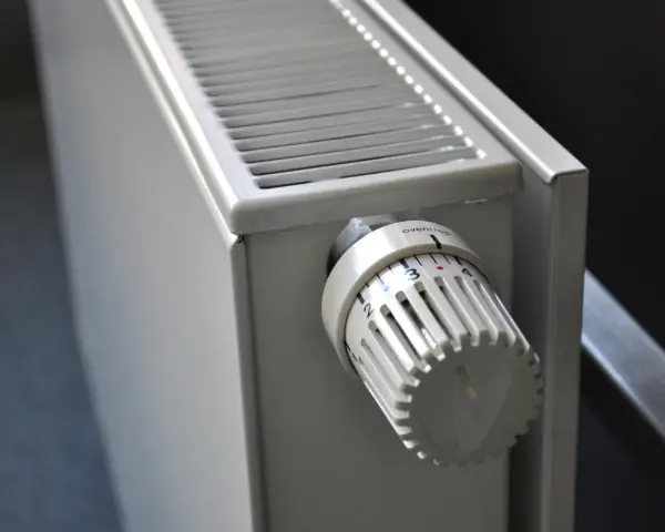 Biały grzejnik z termostatem ustawionym na 3. To element ogrzewania elektrycznego mieszkania, zapewniający komfort cieplny.