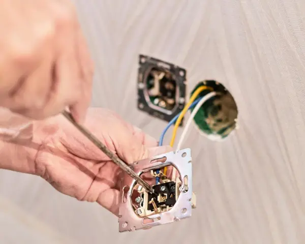 Instalator podłącza podwójny włącznik światła, pokazując jak podłączyć włącznik światła podwójny trzy przewody.