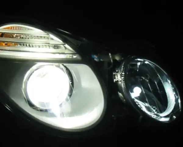 Jasny ksenon rozświetla reflektor, ukazując jego nowoczesny design i pomarańczowe kierunkowskazy.