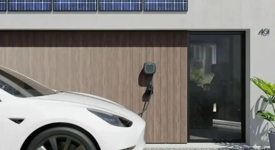 Białe auto elektryczne (BEV) podłączone do ładowarki przy nowoczesnym domu z panelami słonecznymi.
