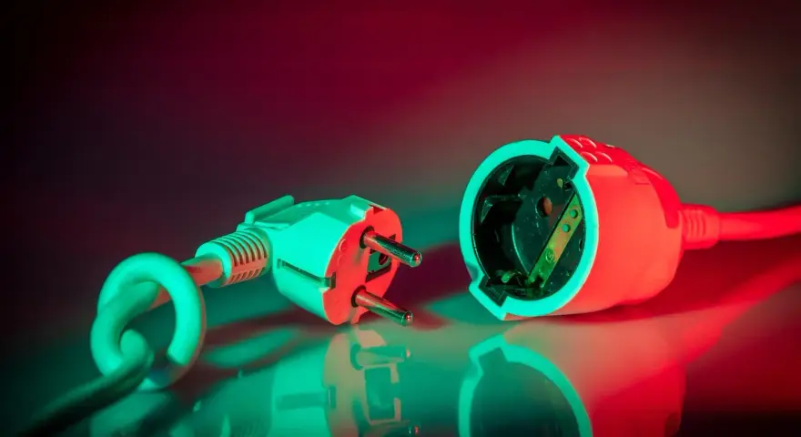 Wtyczka i gniazdko elektryczne, symbolizujące potrzebę zabezpieczenia nadprądowego.