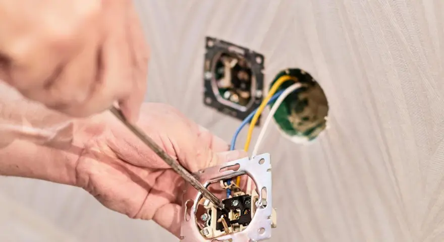 Instalator podłącza podwójny włącznik światła, pokazując jak podłączyć włącznik światła podwójny trzy przewody.