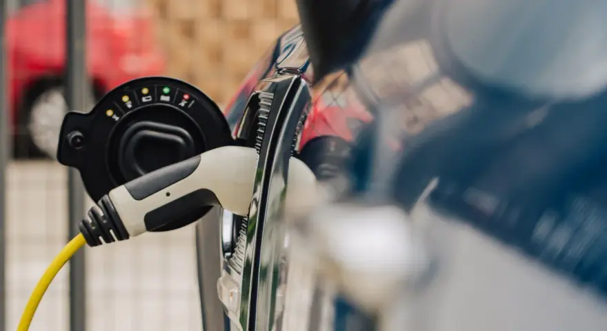 Ładowanie samochodu elektrycznego do 30 tys. zł. Wtyczka z żółtym kablem podłączona do portu ładowania.