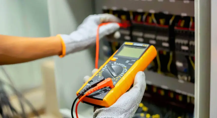 Elektryk sprawdza instalację multimetrem. Poznaj wymiana instalacji elektrycznej koszt i dowiedz się, jak uniknąć nieprzewidzianych wydatków.