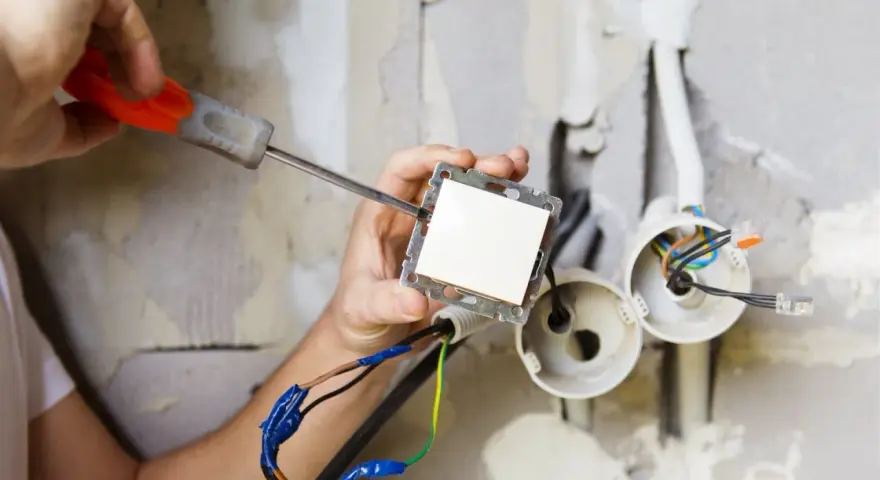 Elektryk montuje włącznik światła. Zastanawiasz się, ile kosztuje prąd budowlany?