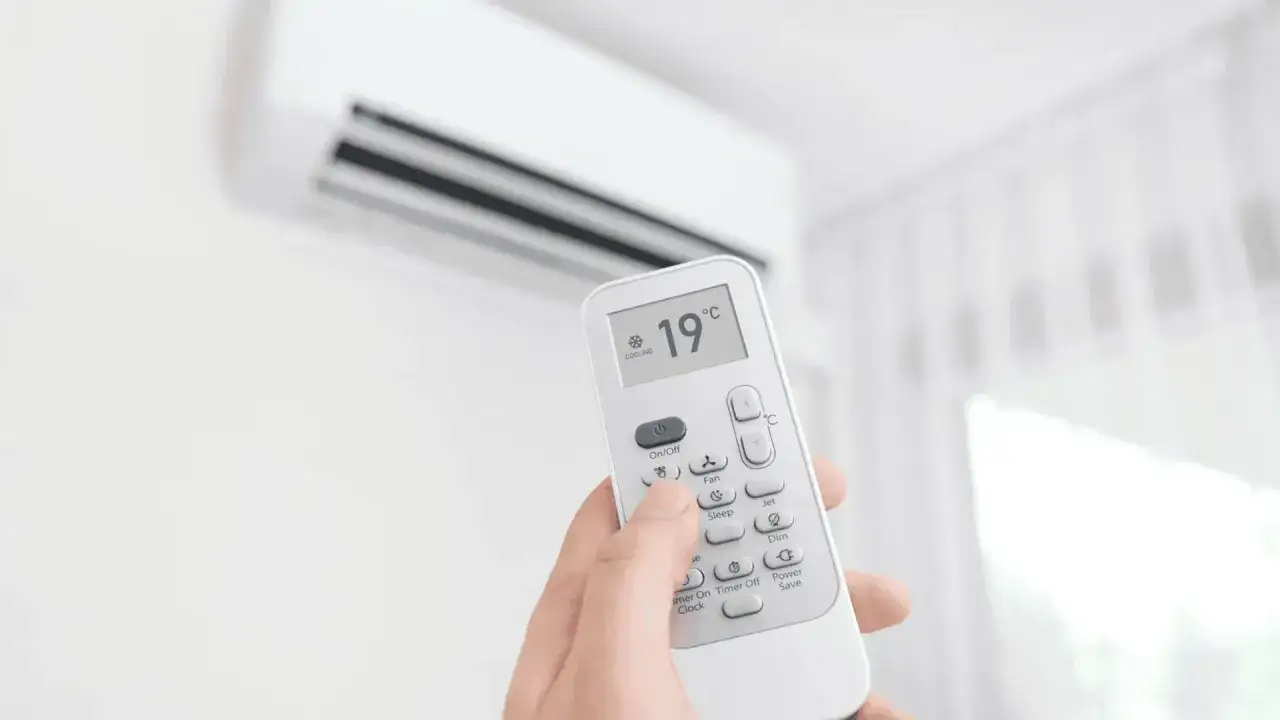 Dłoń trzyma pilot do klimatyzacji ustawionej na 19°C. Kontroluj ustawienia, by obniżyć miesięczny koszt klimatyzacji.