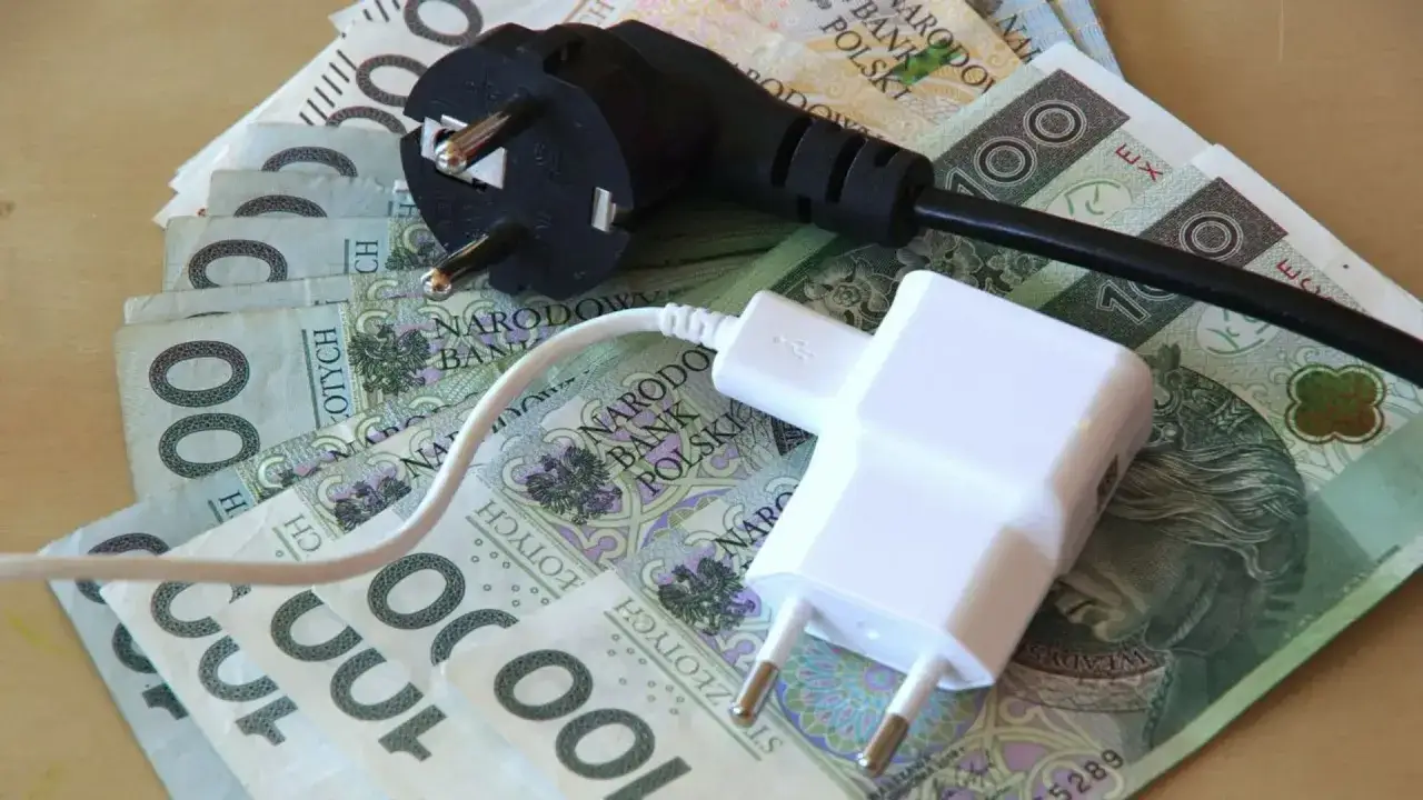 Wtyczki i ładowarka na banknotach 100 zł. Symbolizują wysokie koszty energii, czyli dodatek energetyczny.